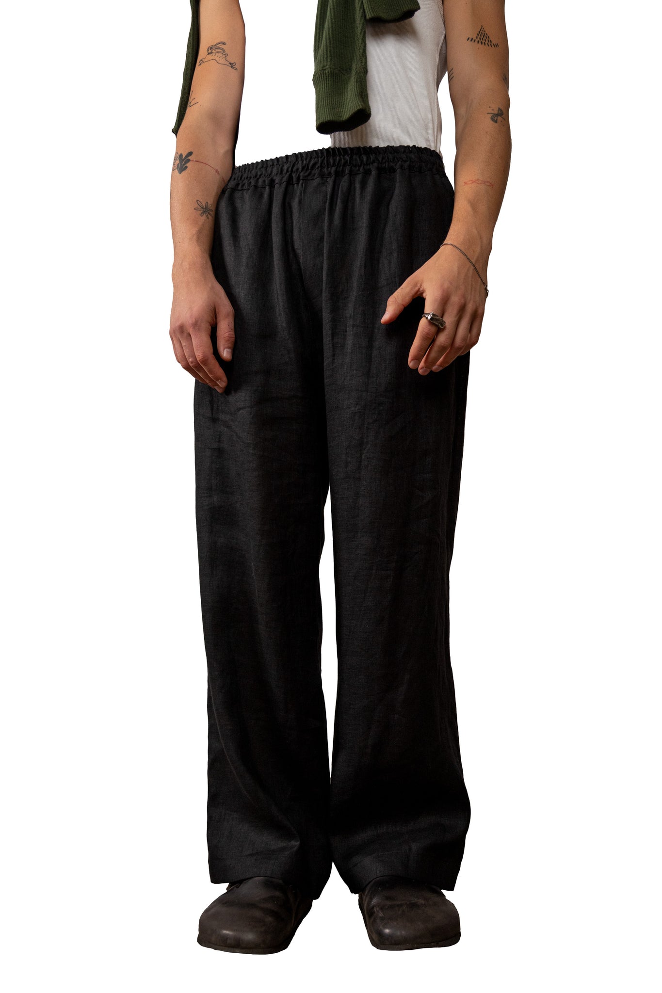 Person wearing black wide-leg linen pants on a white background